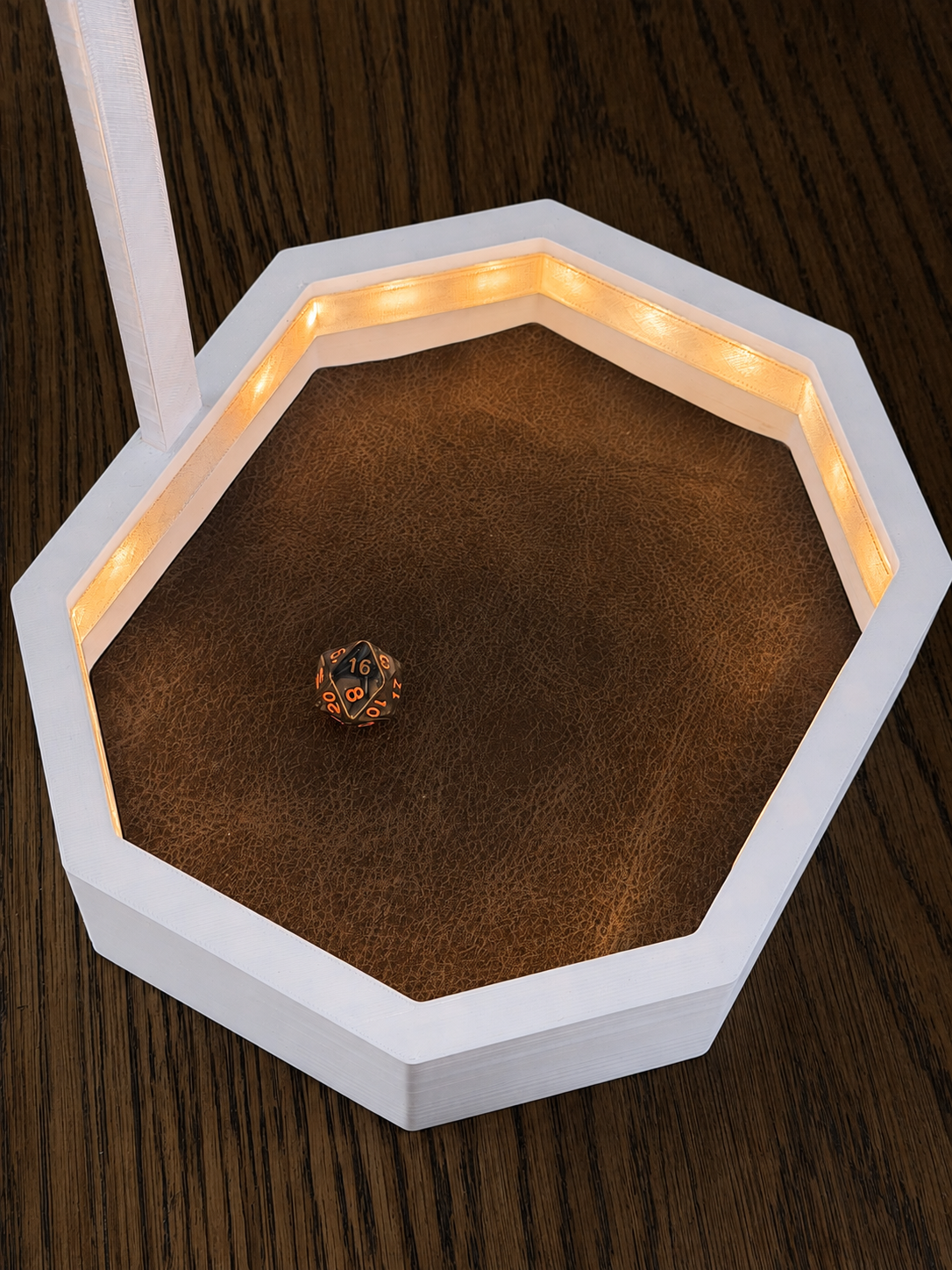 White octagonal OmniRoll prototype dice tray with warm amber LED lighting and a physical d20